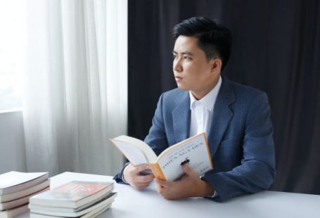 Business - Photo of a Pensive Young Man in a Suit Holding a Book