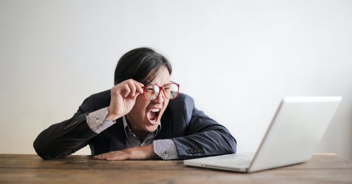 Boss - Modern Asian man in jacket and glasses looking at laptop and screaming with mouth wide opened on white background