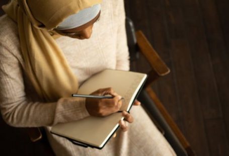Workplace Culture - Crop black Muslim woman writing in planner