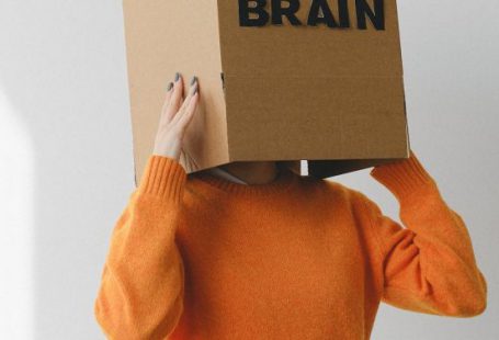 Idea - Crop person putting Idea title in cardboard box with Brain inscription on head of female on light background