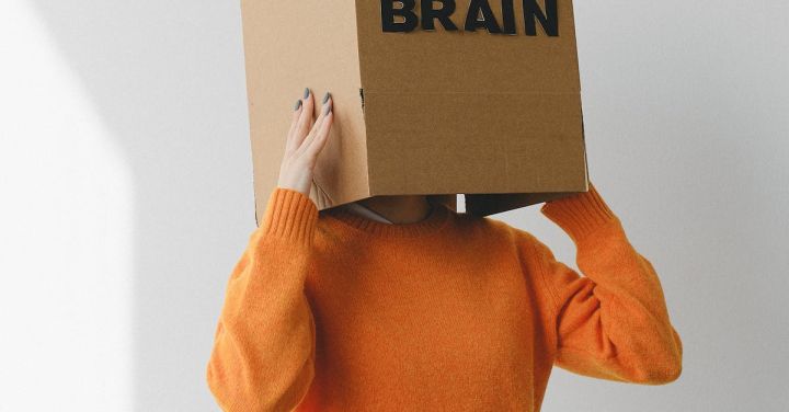 Idea - Crop person putting Idea title in cardboard box with Brain inscription on head of female on light background