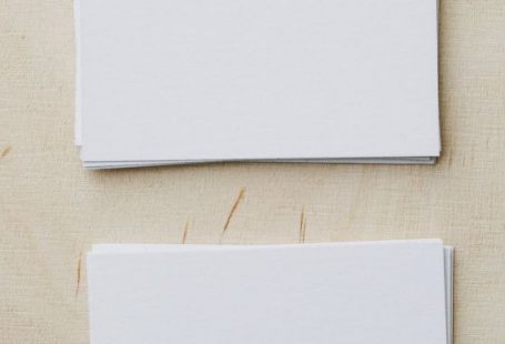 Marketing Campaigns - Top view of stacks of white mockup greeting cards placed on light wooden desk in soft daylight