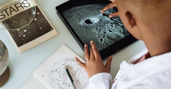 Professional Connections - Crop African American student studying craters of moon on tablet at observatory