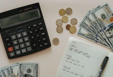 Budgeting - Black Calculator beside Coins and Notebook