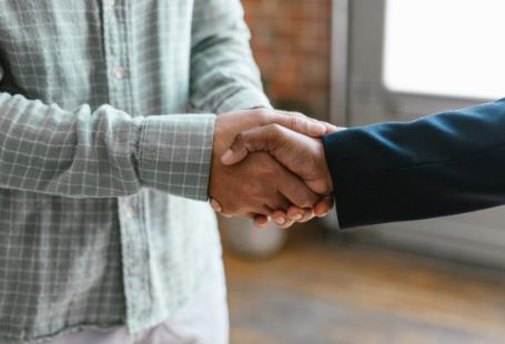 Investor - A Person in Green Plaid Long Sleeve Shirt Shaking Hands with Person in Black Blazer